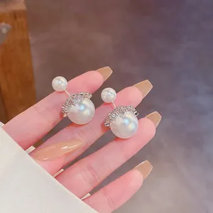 Gros plan de boucles d'oreilles en perles double face avec détails de couronne en strass