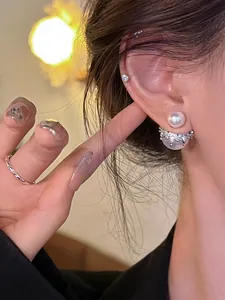 Gros plan de boucles d'oreilles élégantes en perles double face avec couronne argentée.