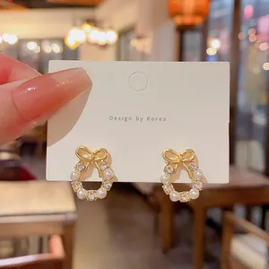 Detailed macro view of elegant gold bow earrings featuring pearls and zircon stones
