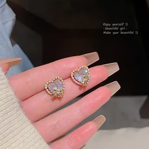 Detailed view of heart zircon stud earrings with pearl border and golden bow accents.