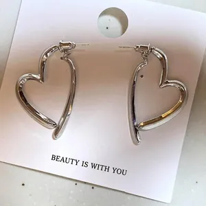Minimalist silver heart earrings with unique cross design on a white card background.