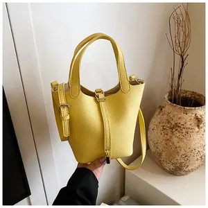 Bright yellow textured bucket bag featuring top handles and adjustable shoulder strap