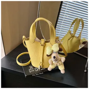 Chic yellow lychee leather bucket bag with a cute dog plush charm and golden lock detail