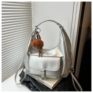 Dettaglio borsa hobo argento metallizzato con ciondolo a orsetto e tracolle multiuso