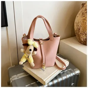 Detailed view of a pink lychee-patterned bucket bag featuring a cute dog plush accessory.