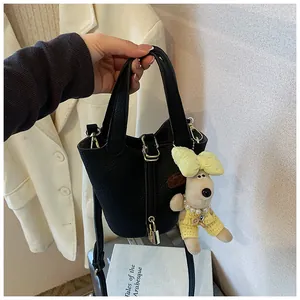 Detailed view of a chic black bucket bag featuring a metal lock and a plush dog charm