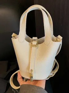 Minimalist white leather bucket bag with gold padlock detail and top handle