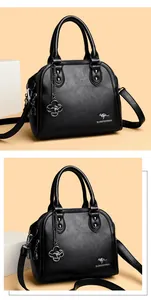 Vista dettagliata dell'elegante borsa a conchiglia in pelle nera con logo canguro