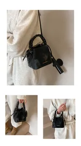 Macro view of black Korean-style bucket bag featuring unique braided handle detail.