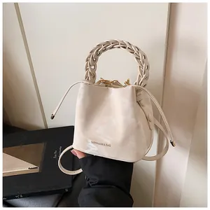 Detailed shot of niche design cream bucket bag with braided handle and logo text