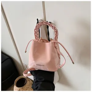 Detailed view of a trendy pink bucket bag featuring a braided handle and marble print