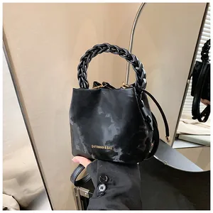 Unique black marble pattern bucket bag with a stylish braided top handle and gold hardware