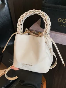 Elegant creamy white bucket bag featuring a unique braided top handle and drawstring closure