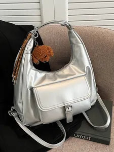 Zaino metallizzato argento da donna con tasca frontale con fibbia e ciondolo di peluche.