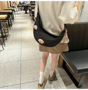 Vue de style rue d'un sac bandoulière en nylon noir avec des breloques mignonnes