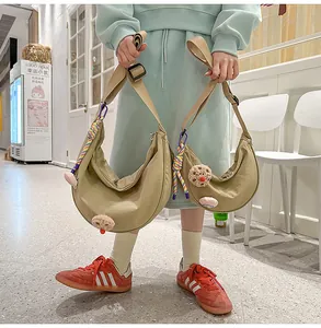 Vue détaillée de sacs demi-lune en nylon kaki avec d'adorables breloques de chien en peluche