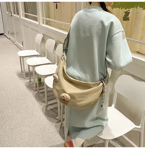 Vue arrière d'un sac dumpling en nylon beige porté par un mannequin dans un café