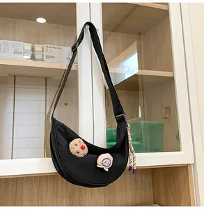 Vue détaillée d'un sac demi-lune en nylon noir avec des patchs de dessins animés et des breloques