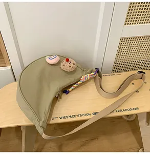 Vue détaillée d'un sac bandoulière en nylon kaki avec breloques en peluche et cordelette.