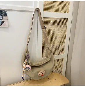 Gros plan d'un sac dumpling en nylon kaki avec breloque colorée et badges en peluche
