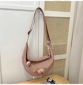 Vue détaillée du sac croissant en nylon rose sur armoire blanche avec breloque ours