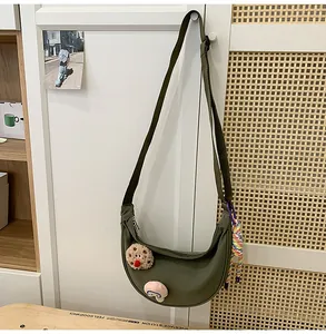 Gros plan d'un sac dumpling en nylon vert suspendu à une porte de placard blanche