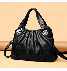 Detalle de bolso negro de cuero sintético con pliegues y anillas plata