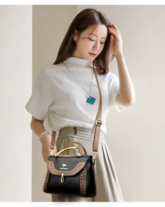 Detailed shot of elegant black crossbody bag with brown braided edges and gold handle
