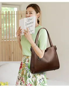 Large brown faux leather shoulder bag with textured finish shown on an elegant model