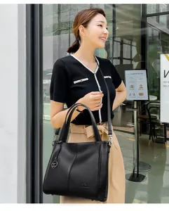 Detail of elegant black leather handbag worn by a model in a urban setting.