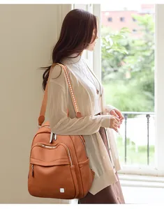 Détail de profil d'un sac à dos en cuir souple marron porté par un mannequin à la lumière.