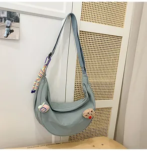 Vue détaillée d'un sac croissant en nylon bleu clair avec d'adorables épingles et pendentifs