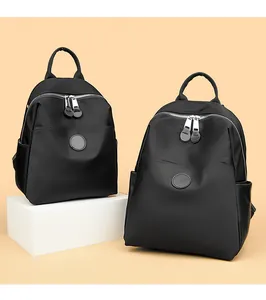 Detailed shot of two black waterproof nylon backpacks for women on a beige background