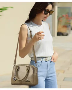 Elegante borsa a conchiglia kaki da donna indossata come borsa a tracolla all'aperto.