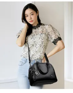 Elegante borsa a mano in pelle nera da donna, abbinata a un top in pizzo e jeans