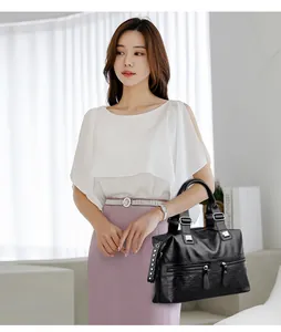 Elegantes Modell mit einer großen schwarzen Lederhandtasche in minimalistischem Studio