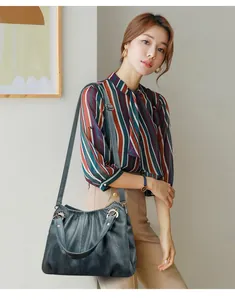 Sofisticado bolso plisado azul marino lucido por modelo con blusa de rayas