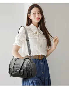 Elegante bolso de mano tipo moto gris con varios bolsillos llevado por una modelo