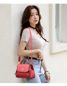 Elegant red leather-textured crossbody handbag featuring a golden kangaroo logo detail