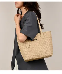 Detail of a beige woven PU leather tote bag worn by a model in a grey blazer.