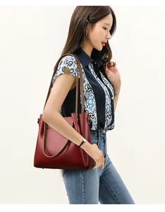 Elegante bolso de mano de cuero texturizado burdeos con correas marrones usado por modelo