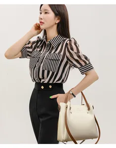 Elegante bolso de mano de cuero blanco crema con correas marrones en una modelo.