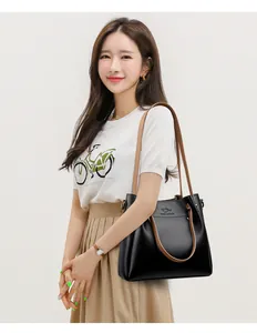 Elegante bolso de hombro de cuero negro con correas anchas marrones en una modelo