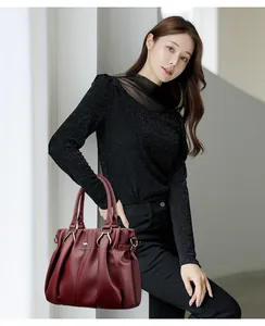 Modelo asiática con un elegante bolso de cuero granate con logo de canguro dorado