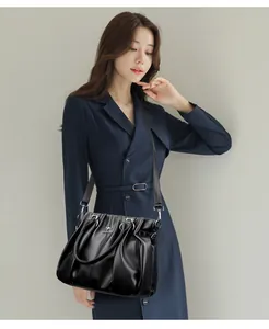 Elegante bolso de mano en cuero plisado negro con correa ajustable usado por una modelo