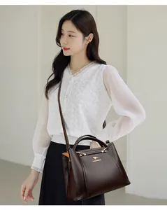 Vista detallada de un elegante bolso de mano de cuero marrón oscuro con un top de encaje blanco