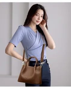 Detalle de un bolso de mano de cuero granulado marrón con bandolera en modelo