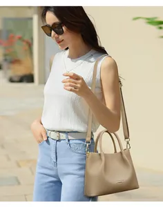 Primer plano de un bolso beige de cuero granulado llevado por una mujer con estilo.