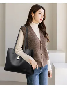 Sac cabas élégant en cuir grainé noir avec fermoir doré porté par un mannequin femme