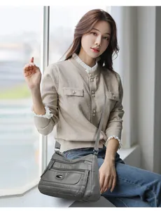 Grey washed leather crossbody bag with multiple zipper pockets worn by Asian model